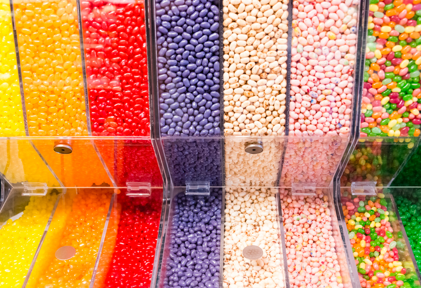 Assorted variety of colorful jelly beans in clear plastic container in a candy store.