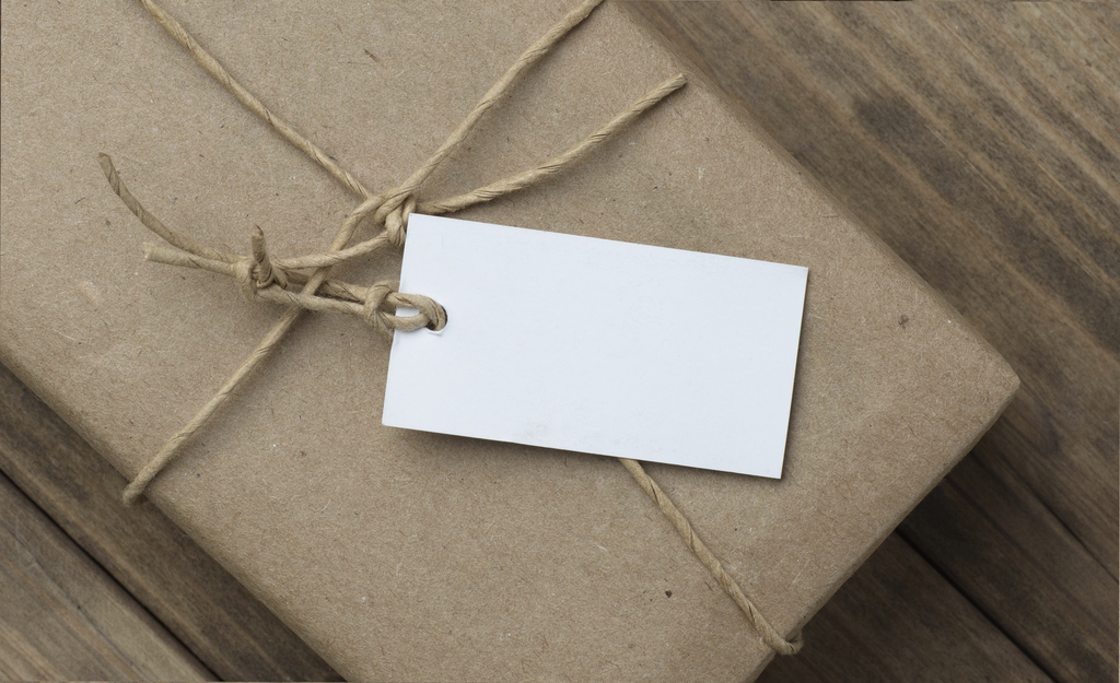 parcel a price tag wrapped in brown kraft paper on wooden table closeup