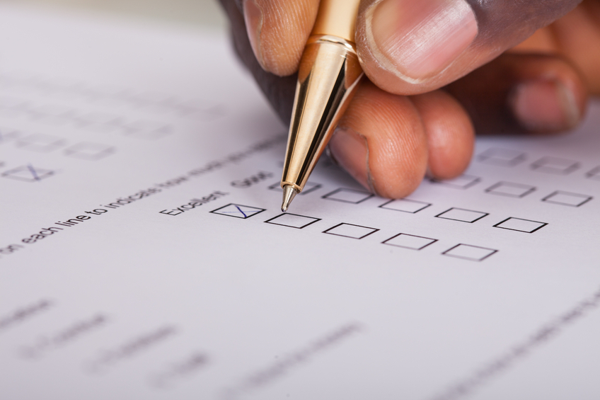 Close-up Of Businessman Filling Customer Survey Form