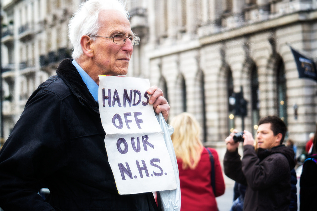 Old man with sign saying hands off our NHS